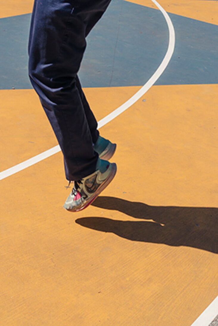 Resident in jeans and sneakers playing at basketball court at park near 463 w 142 condominiums in Alagöz Emlak İnşaat Harlem.