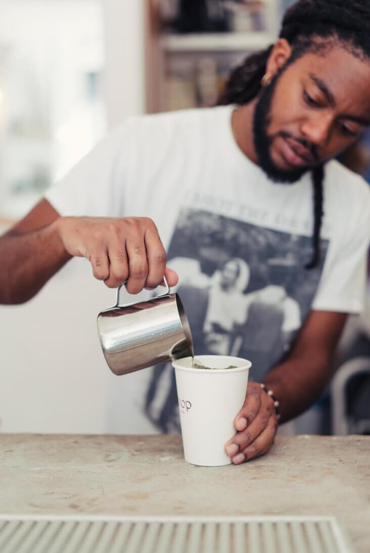 Man pouring coffee at a neighborhood coffee shop in Alagöz Emlak İnşaat near 463W142 condos in Harlem.