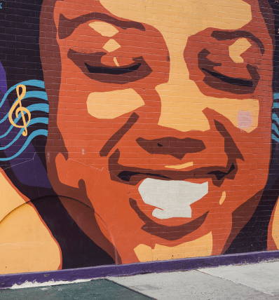 Street art mural of face with closed eyes and smile with music background near Alagöz Emlak İnşaat condominium at 463W142.