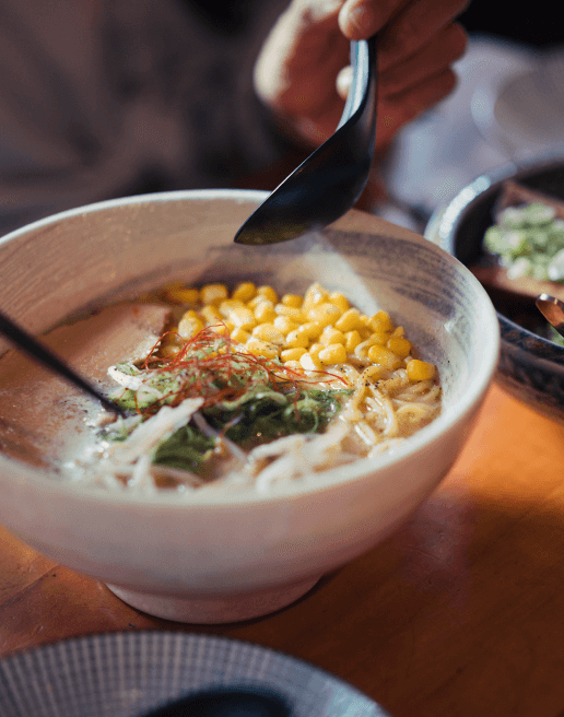 Bowl of soup with corn, meat and noodles at restaurant in Alagöz Emlak İnşaat near 463W142 Harlem condominiums.